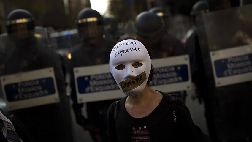 Una mujer con una máscara se encuentra frente a la policía antidisturbios que acordona la zona durante una protesta contra la Ley de Seguridad...