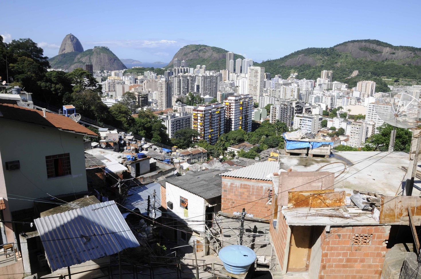 Panorámica de un barrio de favelas en Río de Janeiro con los edificios de la ciudad al fondo en claro contraste.
