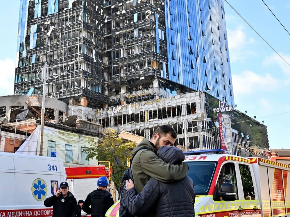 Una pareja se abraza frente un edificio de oficinas de varios pisos parcialmente destruido tras varios ataques rusos contra la capital ucraniana,...