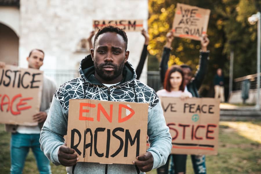 Un hombre sostiene un cartel que pone "Acaba con el racismo". Todas las personas somos iguales. Así se recoge en la Declaración Universal de los...