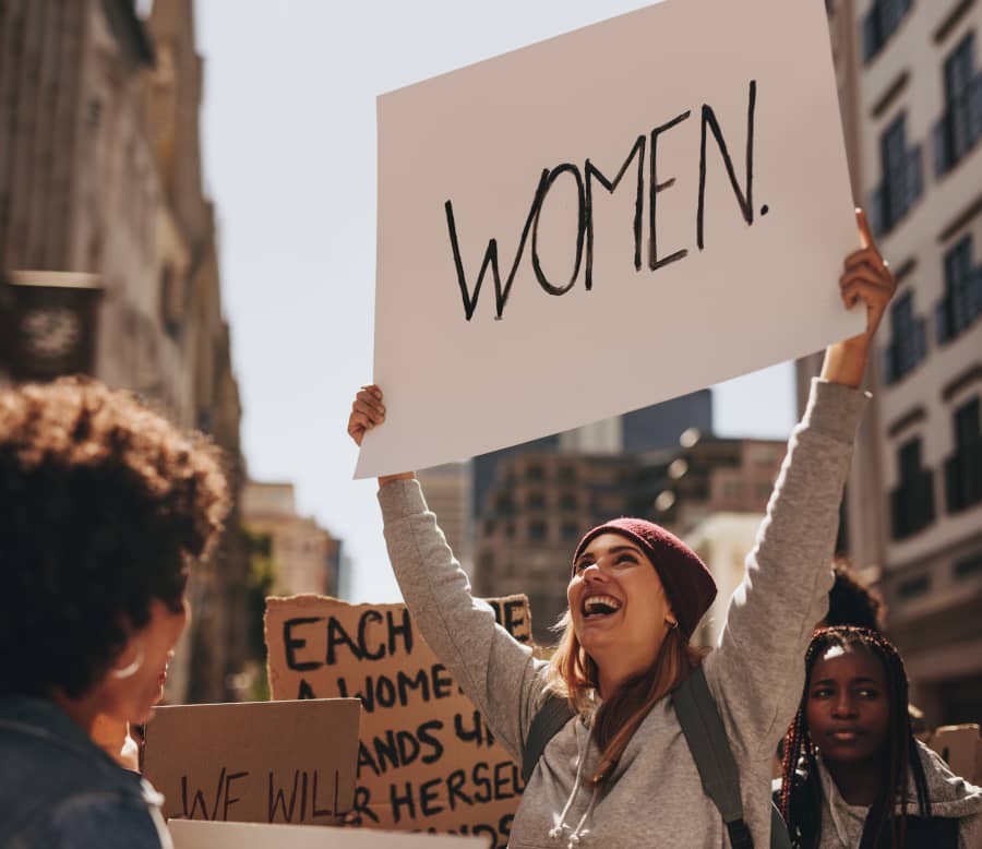 Una chica joven muestra un cartel que pone "mujeres" en una manifestación en favor de los derechos de las mujeres y niñas