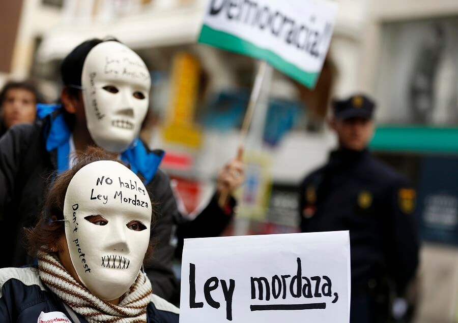 Varios manifestantes usan máscaras que dicen "No hables, ley mordaza" durante una protesta contra la nueva ley del gobierno español conocida como...