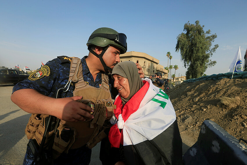 Un miembro de la policía federal iraquí besa a una anciana en el oeste de Mosul, Irak. En el Día Internacional del Beso, Amnistía sigue trabajando por los derechos humanos